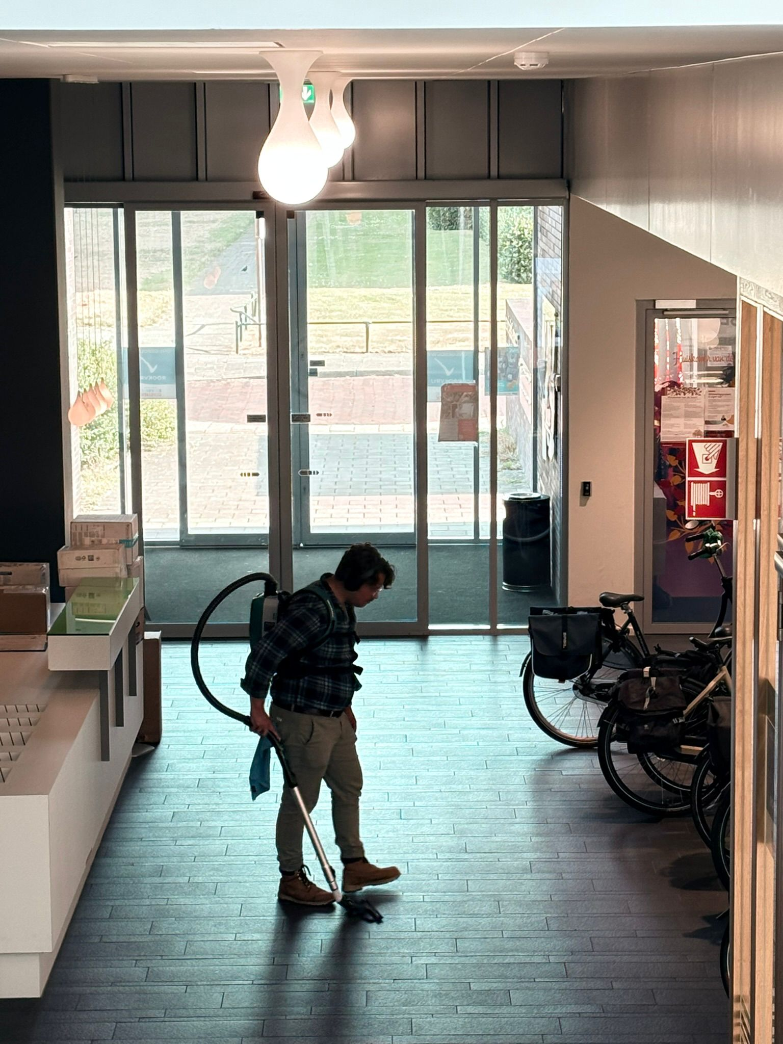 Schoonmaker aan het werk met een stofzuiger in een entree